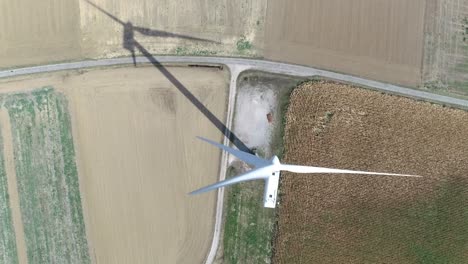 High-aerial-drone-shot-of-windmill-in-between-farmland-with-shadow