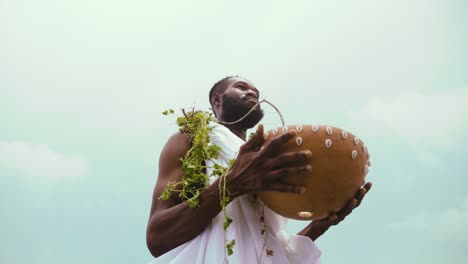 Cámara-Lenta-Y-Tiro-En-ángulo-Bajo-De-Un-Tradicionalista-Africano-Ga-Sosteniendo-Calabaza-Con-Hierba-En-El-Cuello-Usando-Tela-Blanca-Durante-La-Libación