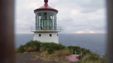 Makapu'u-Point-Lighthouse-overlooking-ocean-through-fence-on-cloudy-day,-Hawaii