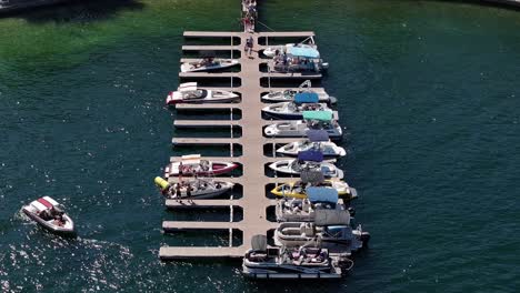 Barco-Yate-Saliendo-Del-Muelle-Retrocediendo-Y-Gente-Disfrutando-De-Un-Buen-Rato-En-El-Lago-Arrowhead-California-Estática-Aérea