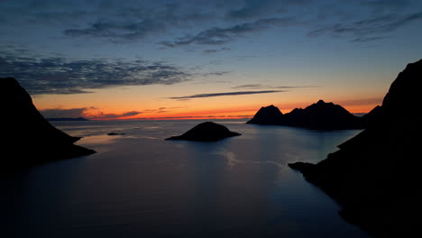 Scenic-blue-hour-drone-view-over-fjord-in-Senja-Norway,-silhouette-of-mountains