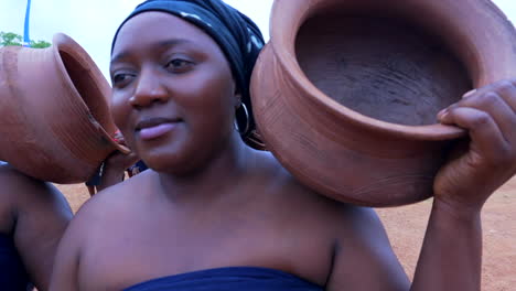 Mujeres-Que-Portan-Vasijas-De-Barro-Dirigen-A-Los-Bailarines-Tribales-Gbagyi-En-Un-Festival-En-Kubwa,-Nigeria