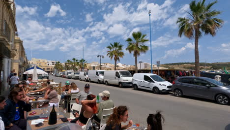 Zeitlupenaufnahme-Eines-Autos,-Das-An-Leuten-Vorbeifährt,-Die-In-Einem-Café-In-Valletta,-Malta,-Essen