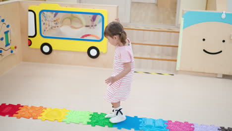 3-jähriges-Vorschulmädchen,-Das-Auf-Bunten-Holprigen-Texturfliesen-Im-Indoor-Spielzimmer-Läuft