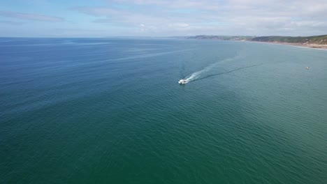 Power-Boat-Along-Whitsand-Beach-Coastline-in-Cornwall,-Aerial-Drone-Shot