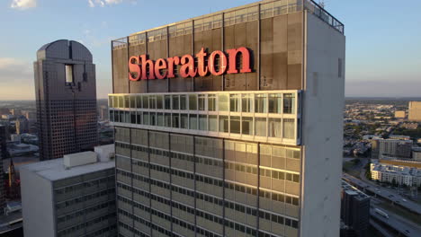 Aerial-view-around-the-Sheraton-logo-on-top-of-the-hotel,-sunset-in-Dallas,-USA