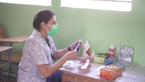 A-female-doctor-prepares-supplies,-instruments-and-equipment-to-care-for-patients-during-a-medical-brigade-in-a-poor-community-in-an-improvised-clinic-in-a-school