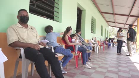 Personas-Sentadas-Esperando-Una-Consulta-Médica-Durante-Una-Brigada-De-Salud,-En-Una-Clínica-Improvisada,-En-Una-Escuela-Comunitaria-Pobre.