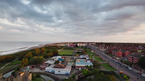 Aerial-video-showcases-a-serene-sunset-over-the-British-seaside-town-of-Skegness,-offering-a-view-of-the-town,-its-promenade,-the-pier,-and-the-coastline