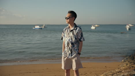 Asian-man-sigh-see-Bali-beach-on-vacation-holiday-with-sunglasses-relaxing