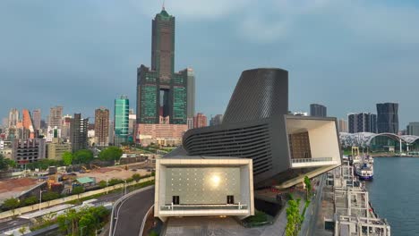 Vista-Panorámica-Aérea-De-La-Terminal-De-Cruceros-De-Kaohsiung-Y-Modernos-Rascacielos-En-La-Ciudad-Al-Atardecer---Movimiento-Hacia-Atrás