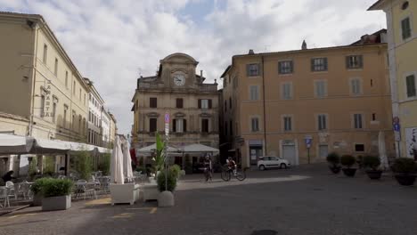 Vista-De-La-Pintoresca-Plaza-&quot;Piazza-Della-Libertà&quot;-En-Spoleto,-Una-Ciudad-De-Umbría-Con-Terrazas-Y-Un-Edificio-Antiguo-Con-Un-Reloj-En-Su-Fachada.