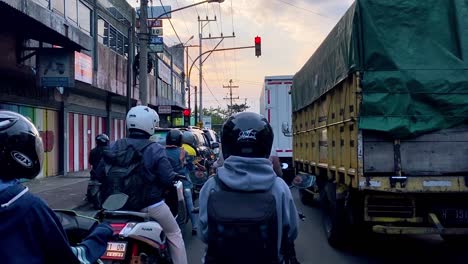Toma-En-Primera-Persona-Del-Tráfico-De-La-Ciudad-De-Indonesia-Durante-La-Puesta-De-Sol:-Muchos-Motociclistas-Y-Camiones-En-La-Carretera