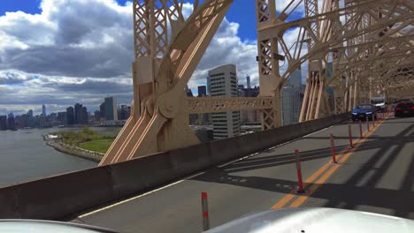 POV-shot-on-Queensboro-bridge-crossing-East-River-in-New-York-City-during-sunny-day-with-skyscraper-buildings-in-background