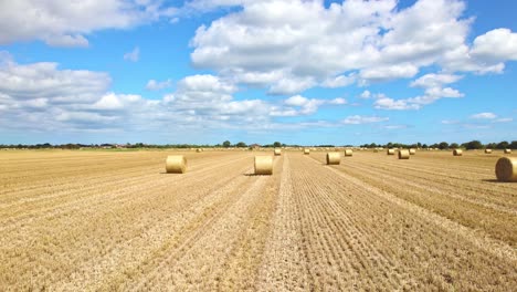 Aerial-footage-captures-the-serenity-of-wind-turbines-in-a-Lincolnshire-farmer's-freshly-harvested-field,-with-golden-hay-bales-adding-a-touch-of-charm-to-the-scene