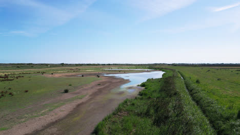 Aerial-footage-displays-the-natural-beauty-of-saltwater-marshlands-on-the-Lincolnshire-coast,-highlighting-seabirds-both-in-flight-and-on-the-lagoons-and-inland-lakes