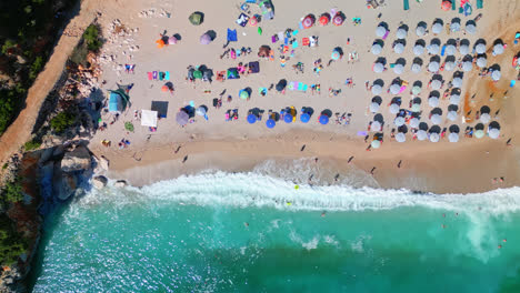 Aerial-drone-top-down-shot-over-clear,-turquoise-Ionian-Sea-water-with-waves-crashing-along-Gjipe-Beach,-Albania-on-a-sunny-day