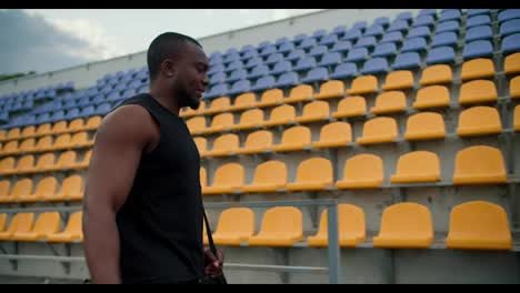 Black-color-Skin-athlete-in-a-black-jersey-walks-through-the-stadium-with-a-bag-and-prepares-for-a-basketball-match