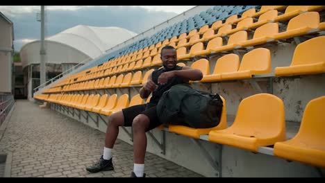 Un-Atleta-De-Piel-Negra-Con-Uniforme-Deportivo-Negro-De-Verano-Saca-Una-Botella-Especial-De-Agua-De-Su-Bolso-Y-La-Bebe-En-El