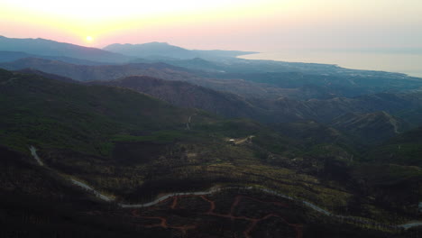 A-drone-rises-over-a-burnt-landscape-next-to-a-mountain-road-in-Pico-De-Los-Reales,-Estepona,-Spain