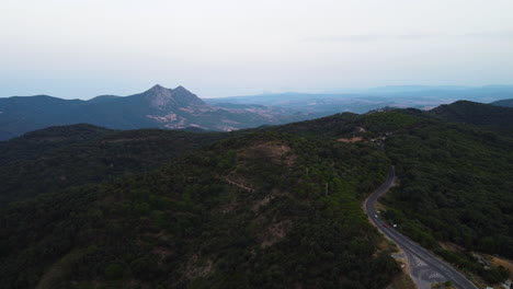 A-drone-aerial-of-a-mountain-road-through-a-forest-of-Pico-De-Los-Reales,-Estepona,-Spain