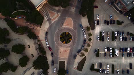 Long-4K-Clip-Aerial-Drone-Rising-on-Decorative-Garden-Pavement-City-Infrastructure-Cars-Traffic-Cobblestone-Roundabout-Roadway-Urban-Downtown-City-Street-Route-Intersection-Junction-Parking-lot