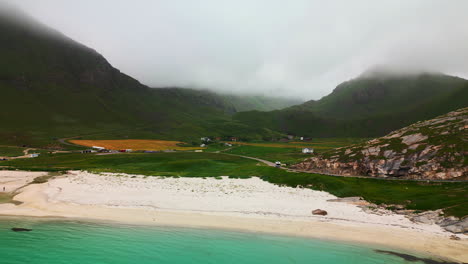 Stunning-white-sandy-shores-of-Haukland-beach,-Lofoten-Norway,-lush-valley-and-clouds-behind
