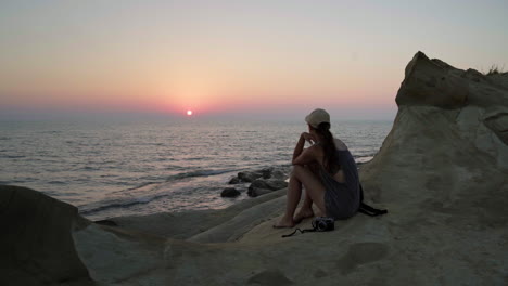 Eine-Frau-Sitzt-Am-Strand-Und-Beobachtet-Den-Sonnenuntergang