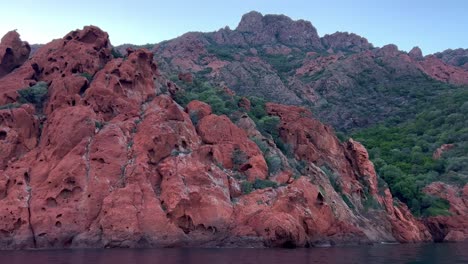 Incredible-red-eroded-rock-formations-of-Scandola-nature-reserve-seen-from-tour-boat-in-summer-season,-Corsica-island-in-France