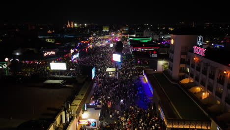 Flying-over-night-lit-streets-of-Aguascalientes,-during-the-San-Marcos-fair---Aerial-view