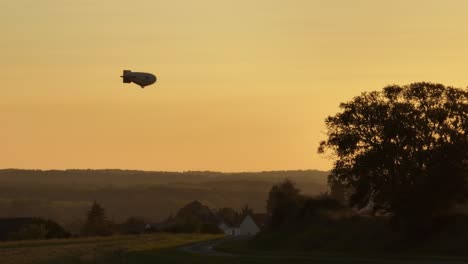 Beautiful-golden-hour-sky-with-silhouette-of-airship-gently-gliding-on