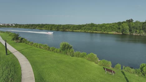 An-aerial-view-panning-left-to-right-of-a-cigarette-boat-style-power-boat-speeding-up-Clear-Creek-on-a-sunny-day-under-blue-skies-in-Nassau-Bay-Texas