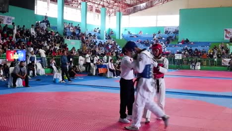 Taekwondo-practitioners,-two-young-men-wearing-doboks-fighting-on-stage-during-Taekwondo-tournament