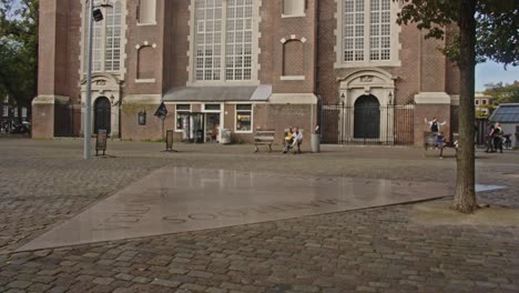 People-walking-across-tile-of-the-Amsterdam-homomonument