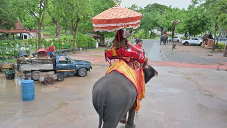 Foreign-and-local-tourists-taking-an-elephant-ride-on-a-rainy-afternoon-at-the-UNESCO-World-Heritage-Historical-Park-in-Ayutthaya-province-in-Thailand