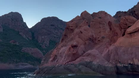 Eroded-red-rocks-of-Scandola-UNESCO-nature-reserve-seen-from-sailing-boat-in-summer-season,-Corsica-island-in-France
