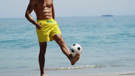 Man-playing-football-at-beach
