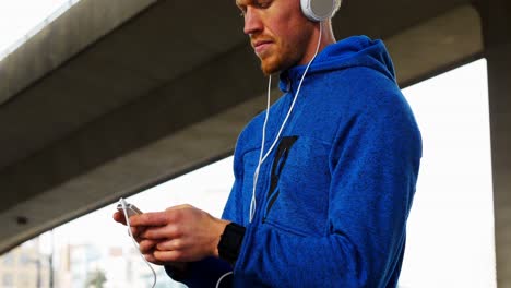 Young-man-with-headphones-listening-to-music-on-mobile-phone,-4K-4k