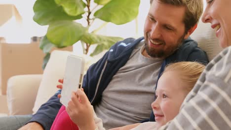 Happy-family-sitting-on-sofa-and-using-a-tablet-in-their-new-home-4K-4k