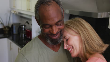 Happy-romantic-diverse-senior-couple-slow-dancing-in-kitchen