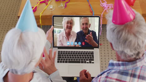 Caucasian-senior-couple-wearing-party-hats-on-laptop-video-chat-during-christmas-at-home