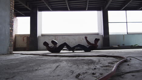 African-american-man-and-woman-exercising-with-medicine-ball-in-an-empty-urban-building