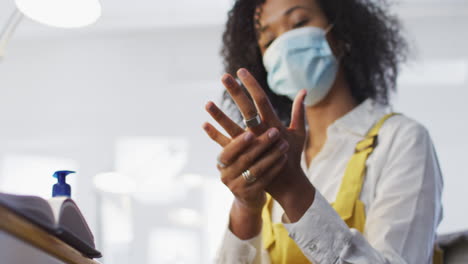 Woman-wearing-face-mask-sanitizing-her-hands-at-office