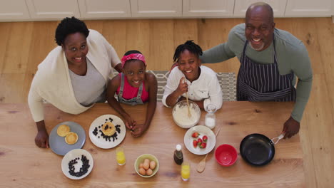 Blick-Von-Oben-Auf-Afroamerikanische-Großeltern-Und-Enkelkinder,-Die-In-Der-Küche-Pfannkuchen-Zubereiten