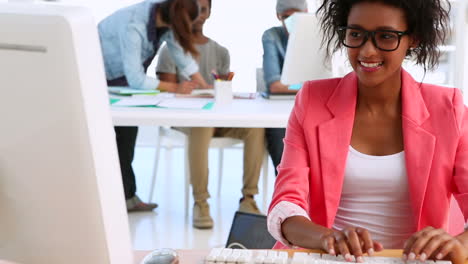 Bonita-Diseñadora-Trabajando-Con-Colegas-Hablando-Detrás-De-Ella.