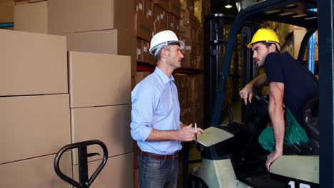 Warehouse-manager-working-with-foreman-in-forklift-
