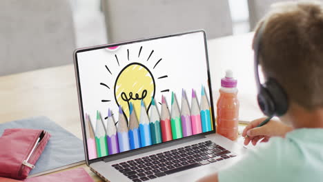 Caucasian-boy-using-laptop-for-video-call,-with-coloured-pencils-and-light-bulb-on-screen