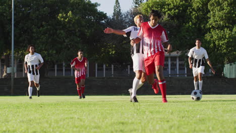 Video-Einer-Vielfältigen-Gruppe-Männlicher-Fußballspieler-Auf-Dem-Feld,-Die-Fußball-Spielen