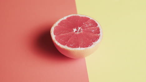 Vídeo-De-Pomelo-Rojo-En-Rodajas-Con-Espacio-Para-Copiar-Sobre-Fondo-Naranja-Y-Amarillo