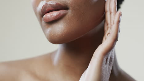 Labios-De-Una-Mujer-Afroamericana-Con-Pelo-Corto-Y-Oscuro-Sobre-Fondo-Beige,-Cámara-Lenta